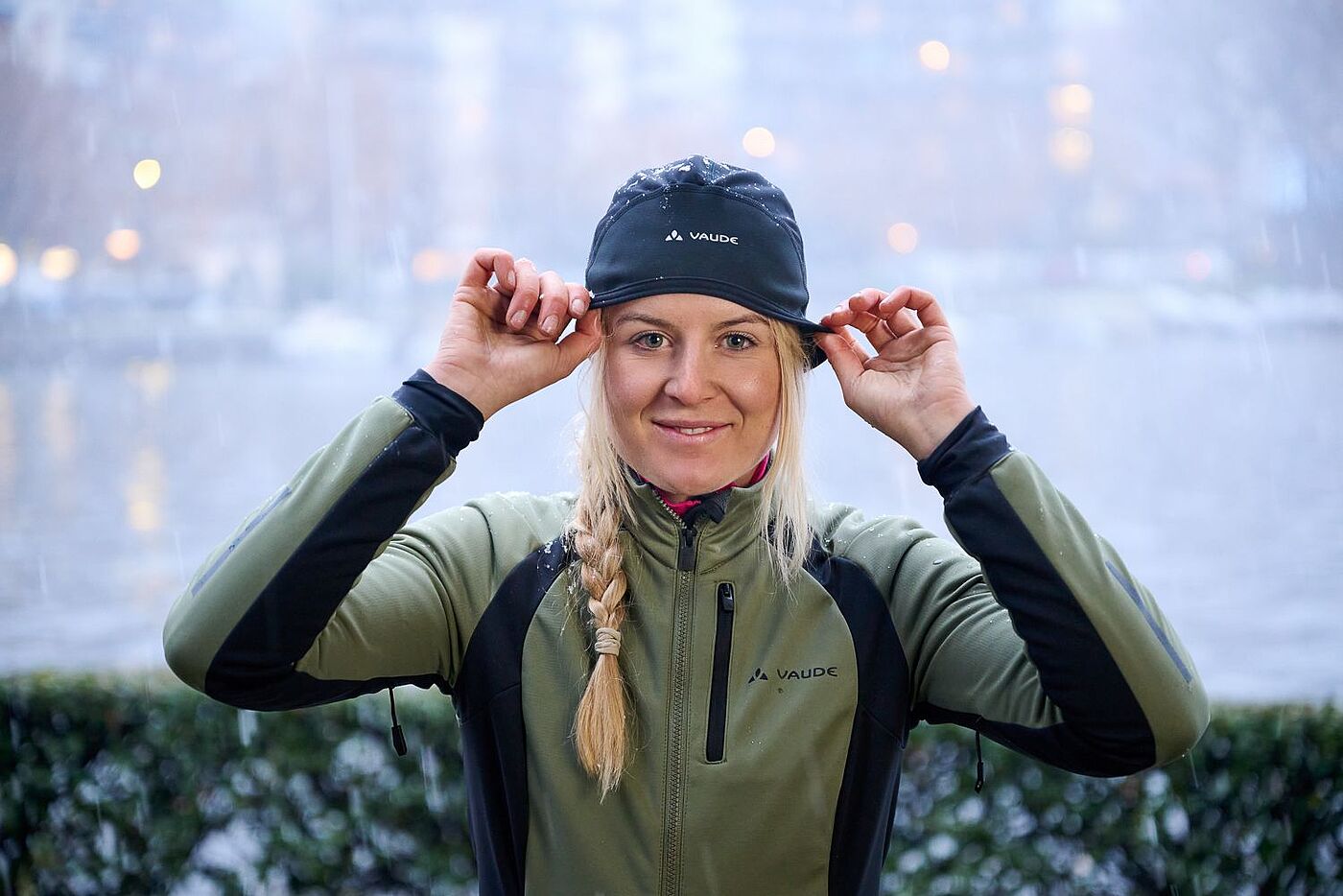 Eine Frau in Radkleidung setzt sich eine Helmmütze auf. 